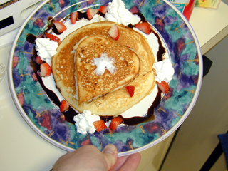 really yummy looking pancakes with berries, chocolate, and whipped cream.